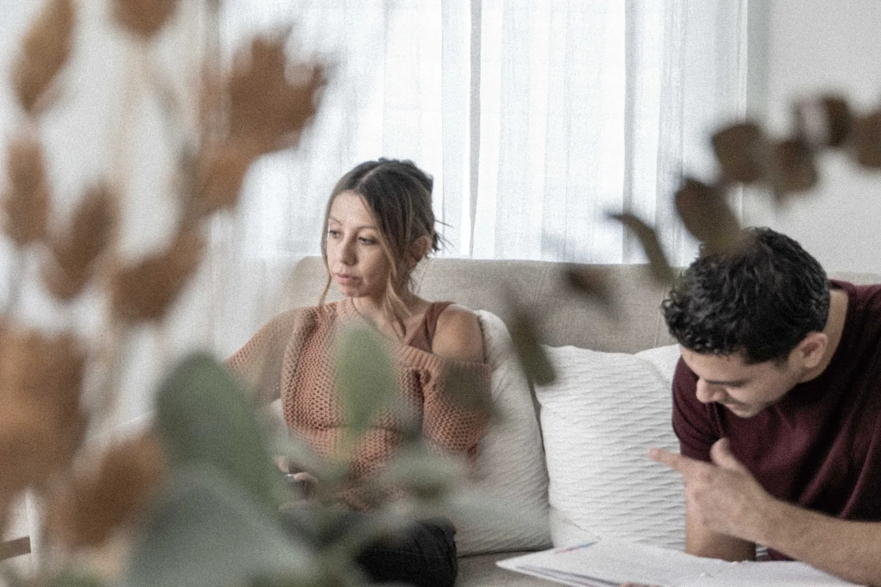 A performer and filmmaker seated on a sofa with script pages during Recovery scene preparation.